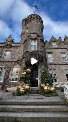 an old castle with christmas decorations on the front steps and wreaths around the entrance