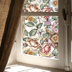 an open window with flowers painted on the glass and blinds pulled down to let light in