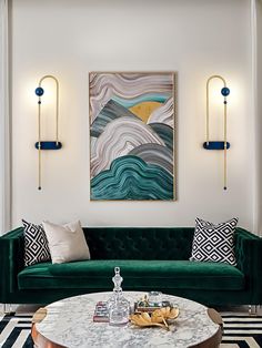 a living room with green velvet couches and art work on the wall