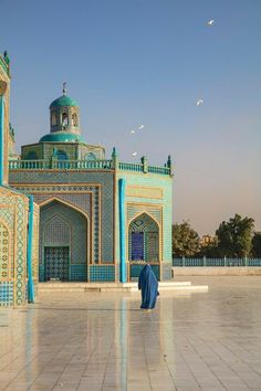 a person standing in front of a building with blue and green tiles on it's sides