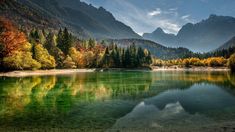 a lake surrounded by mountains and trees in the fall