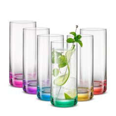 several glasses with different colored liquids and a green leaf in them, all lined up