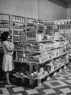 a woman standing in front of a store filled with lots of bottles and cans on shelves