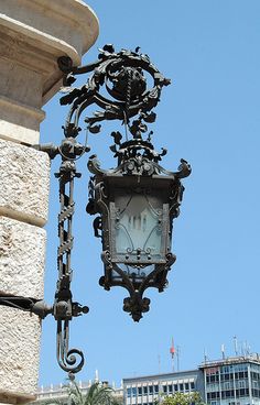 an ornate clock hanging from the side of a building in front of a blue sky