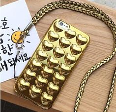 a cell phone case with gold hearts on it and a string attached to the back