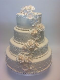 a three tiered wedding cake with white flowers on the top and bottom layer is decorated in frosting