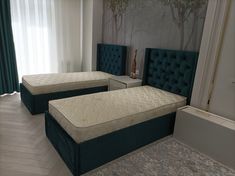 there are two beds in the room with blue headboards on each side and one has a green headboard