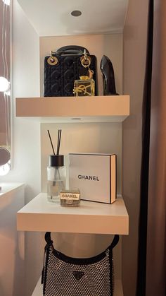 a white shelf filled with chanel items on top of a counter next to a purse