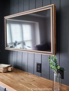 a large mirror hanging on the wall above a wooden table with a vase filled with flowers