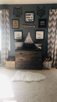 a baby's room with gray walls and chevroned drapes, pictures on the wall