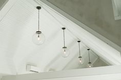 three light bulbs hanging from the ceiling in a room with white walls and vaulted ceilings