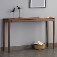 a wooden table with two birds on it next to a basket full of books and a lamp