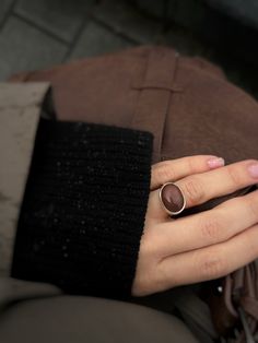 Introducing the exquisite Brown Moonstone Ring, a captivating Cocktail Ring meticulously crafted from high-quality 925 Sterling Silver by Moss Jewellery. This stunning piece seamlessly marries elegance with a touch of mystique, making it a unique addition to your jewelry collection. The focal point of this ring is the mesmerizing Brown Moonstone, renowned for its enchanting play of colors that dance across its surface. The warm, earthy tones of the stone are beautifully complemented by the lustr Modern Open Ring With Large Stone, Elegant Brown Rings With Natural Stones, Modern Silver Rings With Natural Stones, Elegant Opal Ring With Natural Stones, Modern Moonstone Ring With Large Stone For Gift, Modern Moonstone Ring With Large Stone As Gift, Modern Brown Ring Jewelry, Modern Open Ring With Natural Stones, Elegant Oval Ruby Ring With Natural Stones