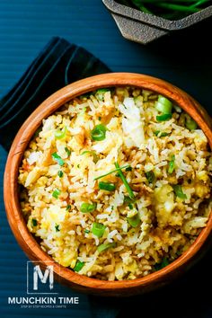 a bowl filled with rice and vegetables on top of a blue table cloth next to a black napkin