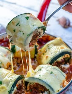 someone holding a fork full of lasagna stuffed with meat, cheese and sauce