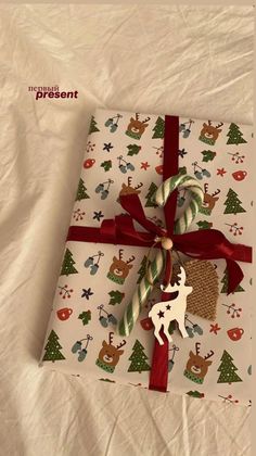 a present wrapped in white paper with red ribbon and a reindeer ornament on it