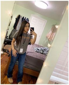 a young woman taking a selfie in her bedroom with lights on the wall behind her