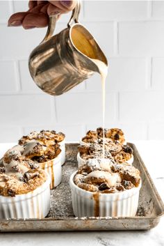 a person pouring syrup over some desserts on a tray