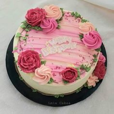 a birthday cake with pink frosting and flowers on it's top, sitting on a table