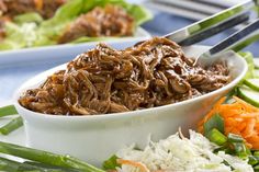 shredded beef in a white bowl with carrots and celery on the side