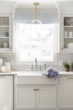 a kitchen with white cabinets and blue flowers on the counter top, along with a green area rug