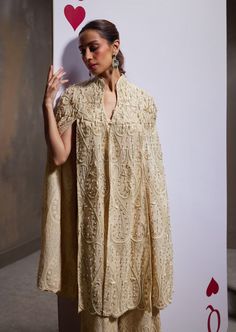 A dazzling showcase of hand embroideries and intricate details, our jane cape set is a masterful creation, featuring an opulently embellished voluminous cape, sumptuously adorned pants, and a charming blouse. Designer Dresses With Intricate Embroidery And Cape Sleeves, Chikankari Embroidery Wedding Dress With Cape Sleeves, Traditional Kaftan With Cape Sleeves For Reception, Traditional Wedding Kaftan With Cape Sleeves, Embroidered Evening Cape Dress, Embroidered Cape Evening Dress, Evening Cape Dress With Embroidery, Elegant Embellished Kaftan With Cape Sleeves, Evening Dresses With Pearl Embroidery And Cape Sleeves