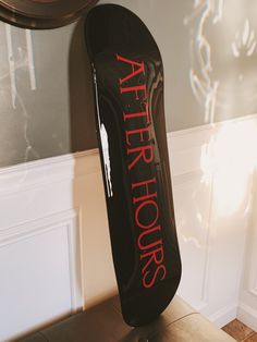 a black skateboard sitting on top of a wooden table next to a wall with red lettering