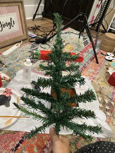 a small christmas tree sitting on top of a table next to a pile of wrapping paper