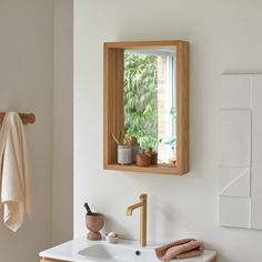 a bathroom with a sink, mirror and towels hanging on the wall next to it