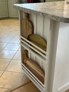 an open cabinet in the middle of a kitchen with utensils and cutting boards