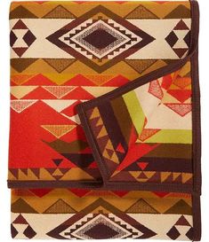 a blanket with an orange, brown and green design on the bottom is folded up