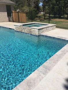 an empty swimming pool with blue water and stone steps leading up to the side of it