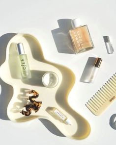 an assortment of beauty products arranged on a white surface, including a comb, nail polish and perfume bottle