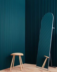 a chair and stool in front of a green wall with vertical slats on it