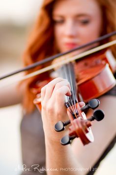 a woman is playing the violin outside