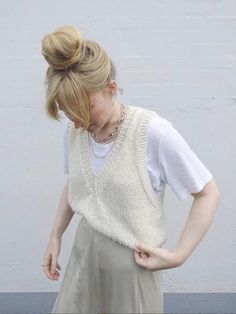 a woman standing in front of a wall with her hands on her hips and looking down