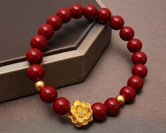 Visist our shop to get more Jewelry ideas and choices! https://www.etsy.com/shop/FamilyJewelryCo Design Name: Strengthful Lotus Design Meaning: The gold lotus and 2 balls rebirth in the surrounded red cinnabar beads means ennergy and strength, purity and rebirth, good luck. Material Lotus & Balls: 24K 999 Gold Red Beads: Red Cinnabar Rope: Elastic Nylon Rope Default Size:  Gold Lotus: 13*13*8.5 MM; Gold Balls: 4 MM (Diameter), about 1-1.1 g Red Beads: 8.5 MM (Diameter) (The Gold Size is fixed, t Gemstone Beaded Bracelets For Festivals And Gifts, Handmade Jewelry With Round Beads For Gifts, Red Round Beaded Bracelets For Festivals, Red Hand-strung Beaded Bracelets For Festivals, Hand-strung Red Beaded Bracelets For Festivals, Traditional Gold Beaded Bracelets With Gemstone Beads, Traditional Red Gemstone Beads Bracelet, Red Beaded Bracelets As Festival Gift, Gold Gemstone Beads For Gift