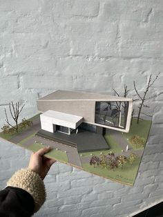 a person holding up a paper model of a house