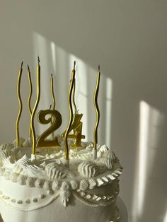 a birthday cake with candles in the shape of number twenty and four on it's white frosting