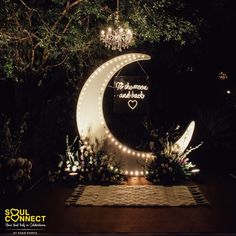 the moon is lit up with lights and flowers on it's side, surrounded by greenery