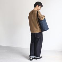 a man holding a blue bag while standing in front of a white wall with his back to the camera