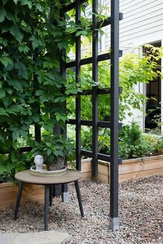 a small table sitting in the middle of a graveled area next to a tall planter