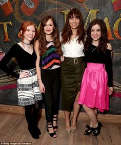 three women standing next to each other in front of a sign