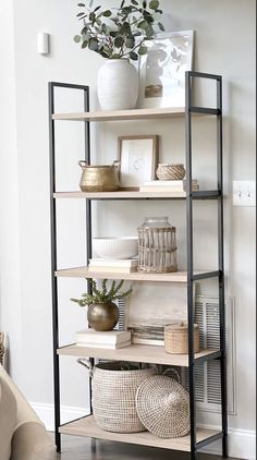 a shelf with baskets and pictures on it in a living room next to a couch