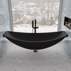 a large black bathtub sitting in front of a window next to a wall mounted faucet