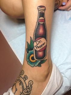 a woman with a tattoo on her leg has a bottle of dr pepper tattooed on it