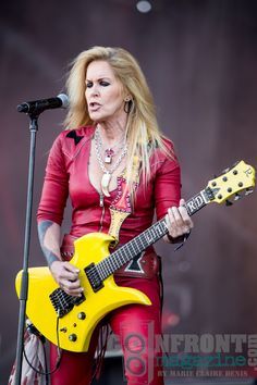 a woman in red holding a yellow guitar