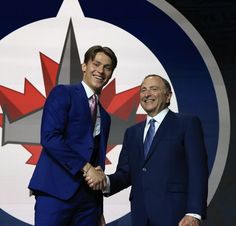 two men shaking hands in front of a wall with a maple leaf logo on it