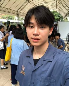 a young man standing in front of a group of people at an outdoor food market