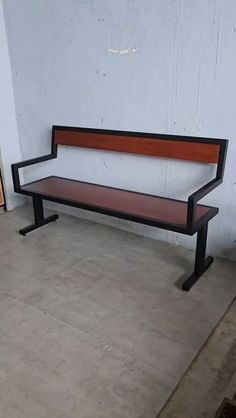 a wooden bench sitting in front of a white wall